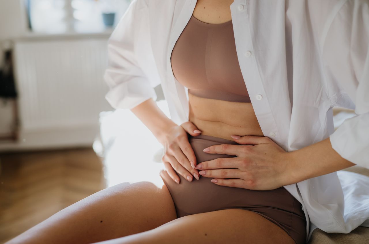 Woman in underwear holding tummy with perimenopause bloating