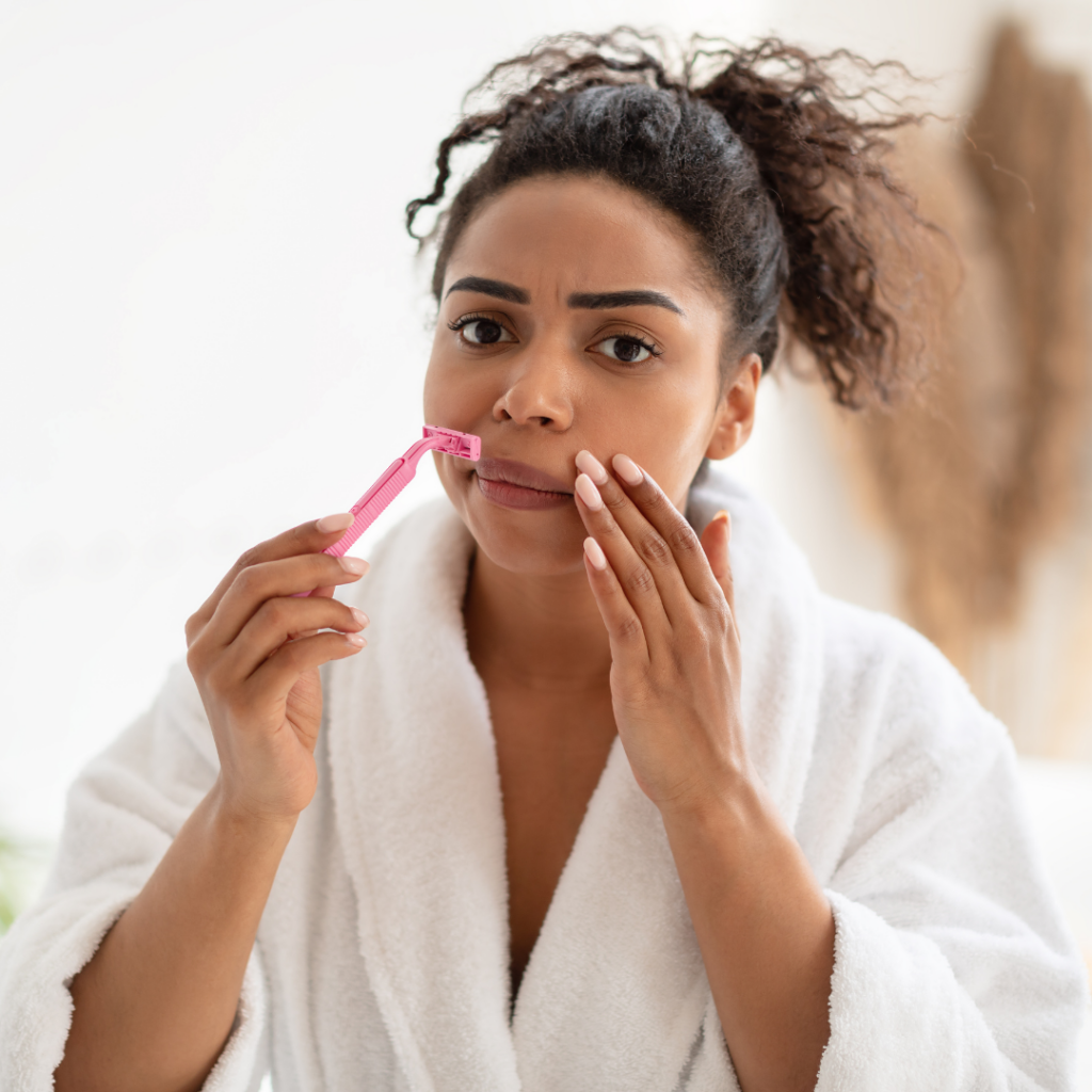 Woman shaving upper lip hair and getting rid of unwanted facial hair in menopause.