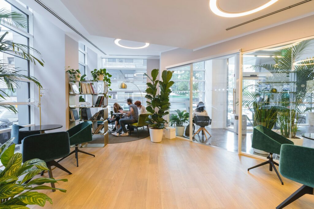 An open office with lots of plants and open windows to help with menopause in the workplace - offering seats by a window to combat hot flashes.