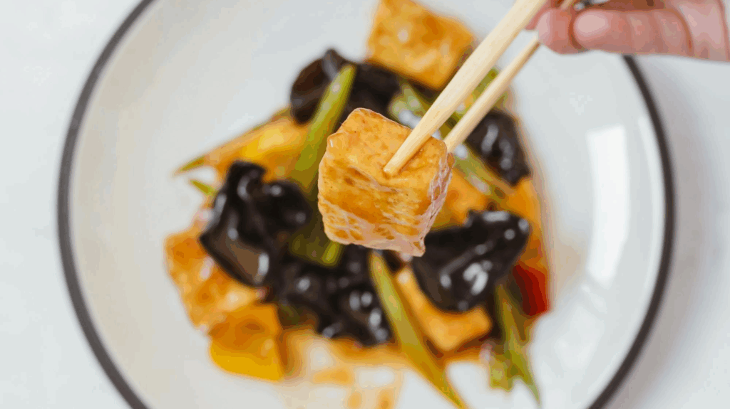 A bowl of air fryer tofu with garlic and honey sauce, accompanied with green beans and mushrooms.