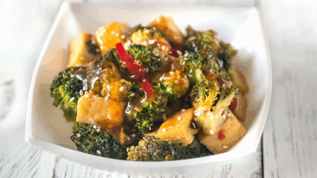A bowl full of air fryer tofu in a sticky sesame sauce, served with broccoli and sesame seeds.