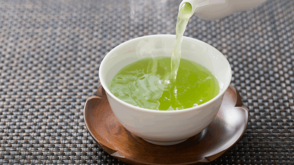 A mug of green tea on a placemat and a wooden saucer. Great drink to combat menopause bloating and IBS