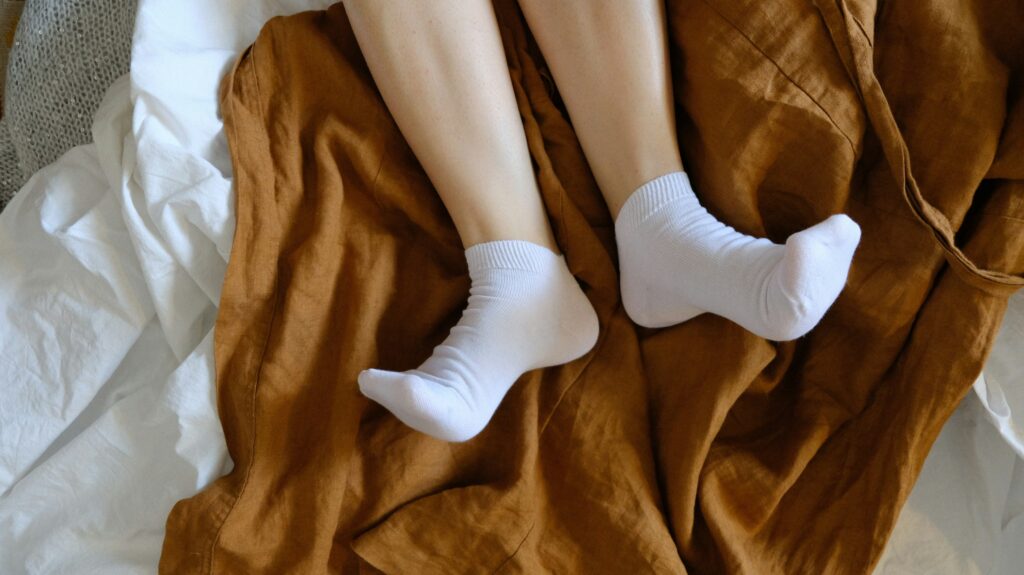 Feet (covered with socks) and legs on a blanket stretching to cope with restless leg syndrome in menopause.