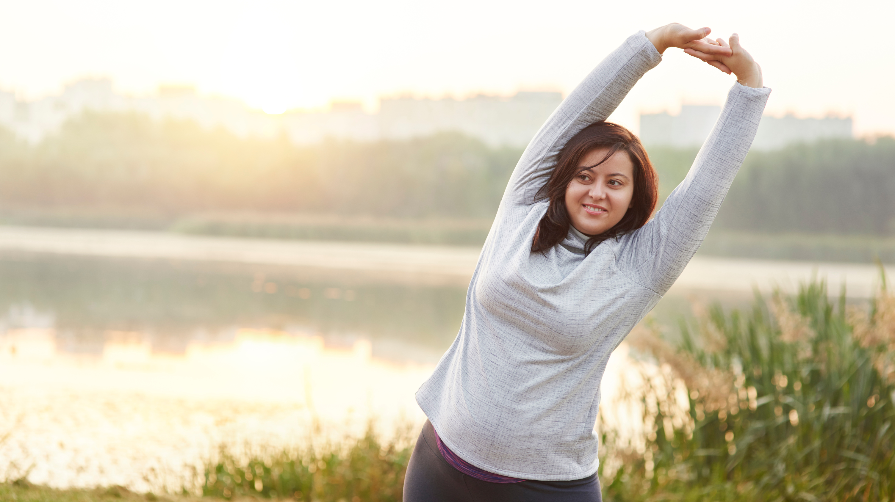 Woman in a grey jumper near a lake doing exercise to tackle menopause and depression