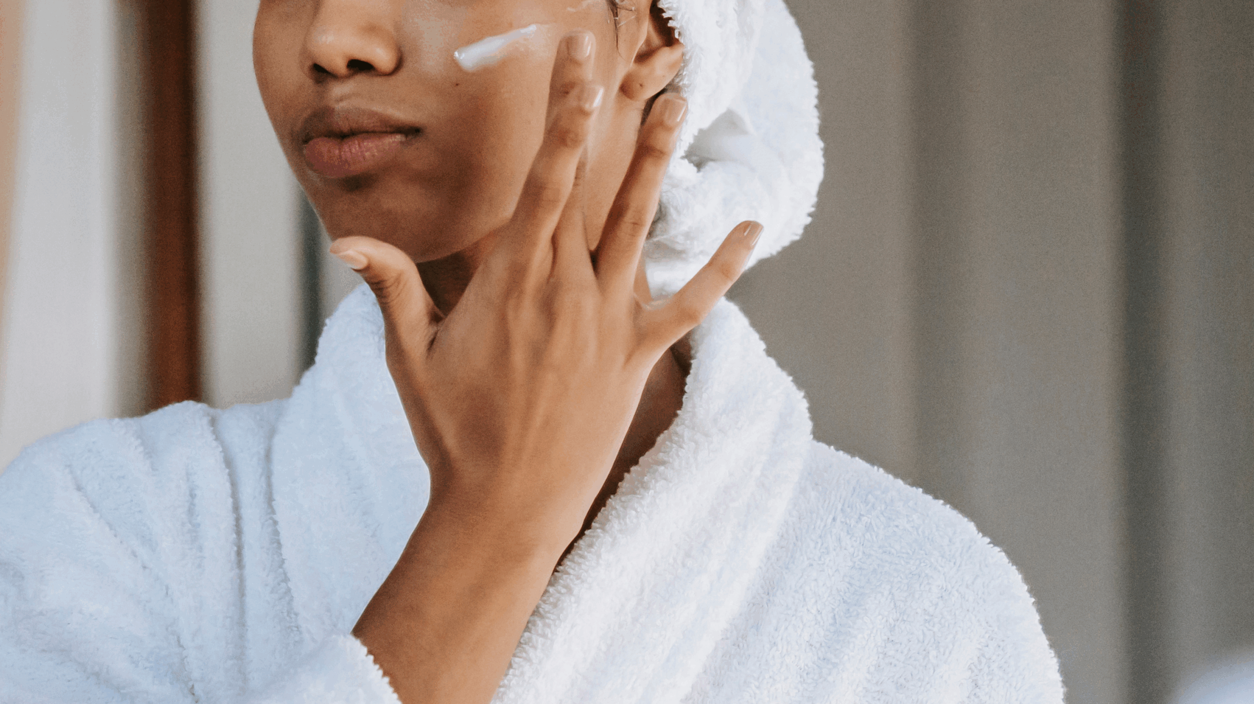 Woman in a bath-robe applying moisturiser to tackle perimenopause itchy skin