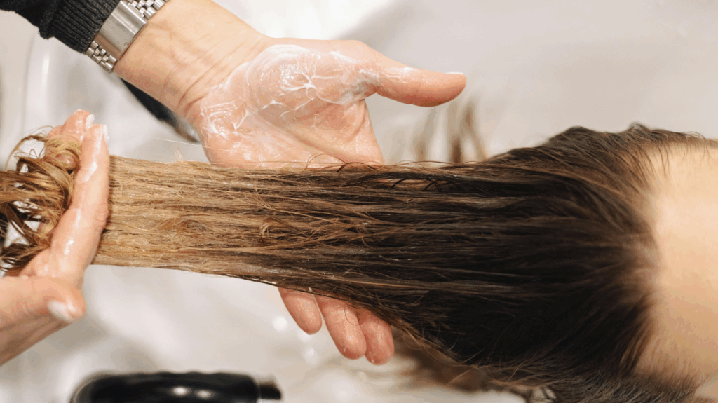 A woman at the hair salon having her hair washed, using gentle hair care methods to tackle perimenopause and hair loss