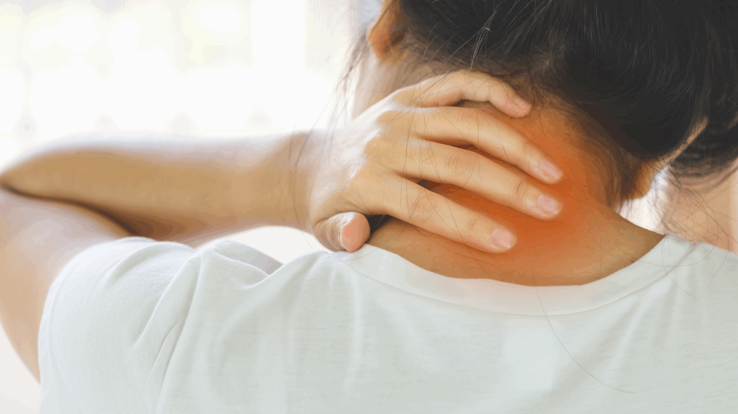 Woman with tied up black hair holding her neck due to joint pain in premature menopause